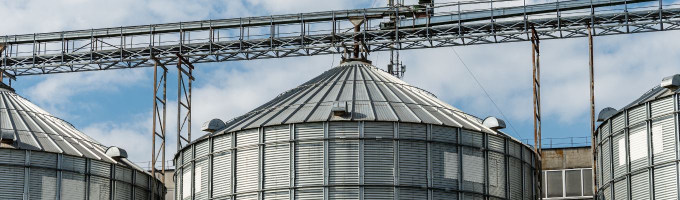 Silos metálicos de armazenamento de grãos em área rural com estrutura industrial.