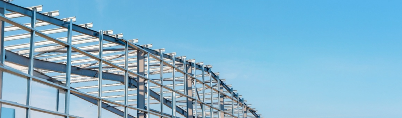 Estrutura metálica de galpão industrial em aço, com vigas e pilares metálicos sem fechamento, em fase de montagem.