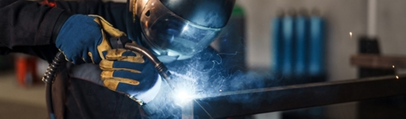 Processo de soldagem em estrutura metálica de aço em ambiente industrial.