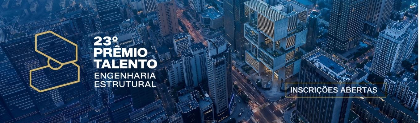 Vista aérea urbana com edifícios modernos e destaque para prêmio de engenharia estrutural com inscrições abertas.