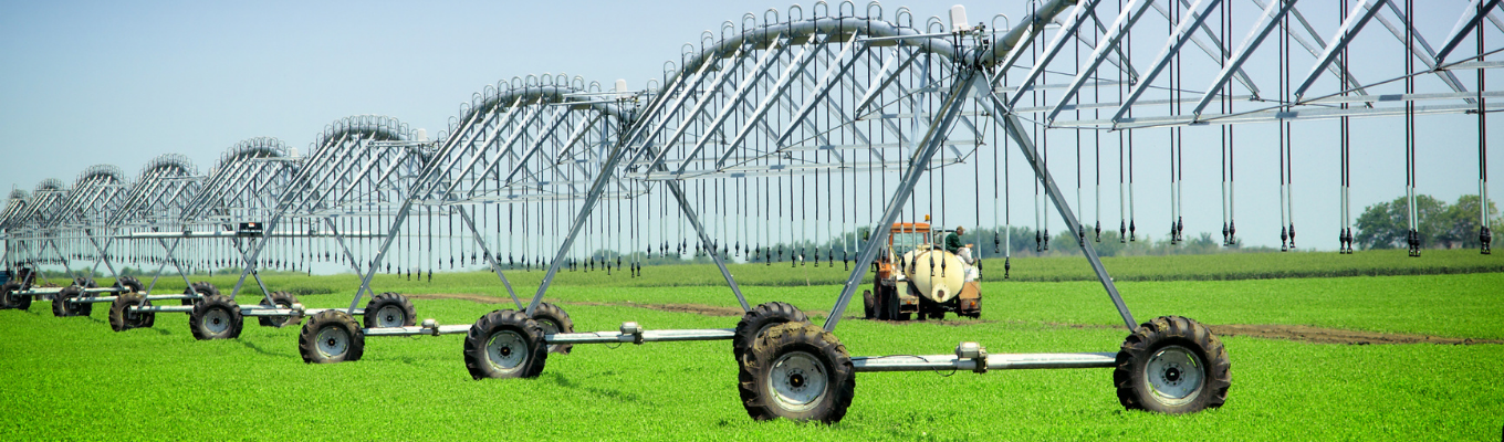 Sistema de irrigação por pivô central com estrutura metálica em área de cultivo agrícola, utilizado para distribuição de água na lavoura.