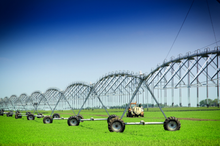 Sistema de irrigação por pivô central com estrutura metálica em área de cultivo agrícola, utilizado para distribuição de água na lavoura.