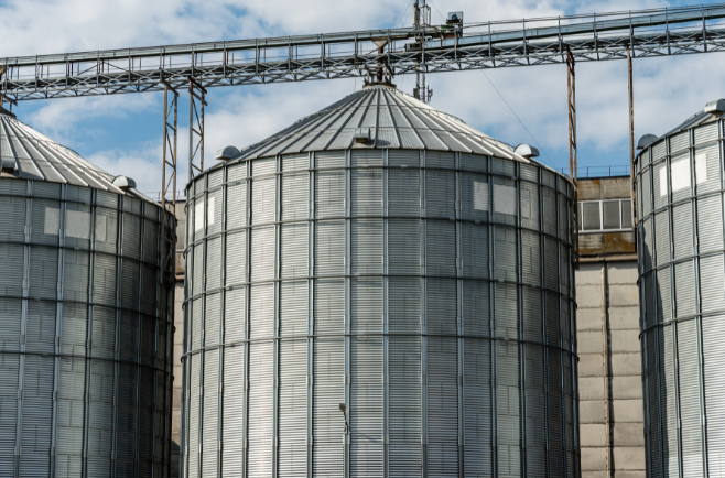 Silos metálicos de armazenamento de grãos em área rural com estrutura industrial.