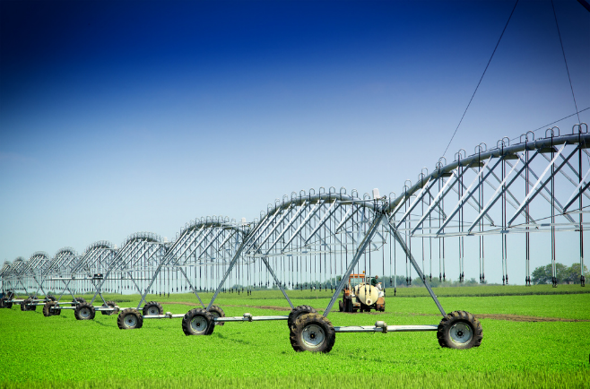 Sistema de irrigação por pivô central com estrutura metálica em área de cultivo agrícola, utilizado para distribuição de água na lavoura.
