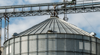 Silos metálicos de armazenamento de grãos em área rural com estrutura industrial.