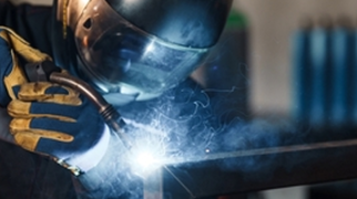 Processo de soldagem em estrutura metálica de aço em ambiente industrial.