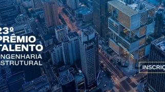 Vista aérea urbana com edifícios modernos e destaque para prêmio de engenharia estrutural com inscrições abertas.