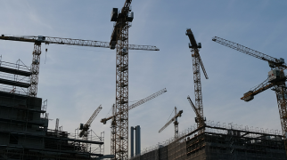 Guindastes e estruturas metálicas em canteiro de obras da construção civil.